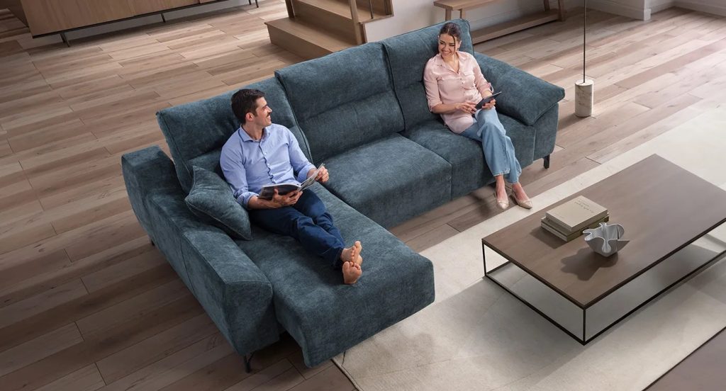 Divano angolare blu con chaise longue al centro della stanza, zona relax in open space