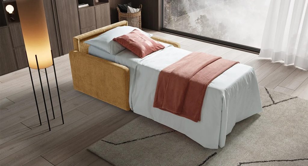 Divano letto piccolo aperto in tessuto senape, soluzione salvaspazio per ospiti